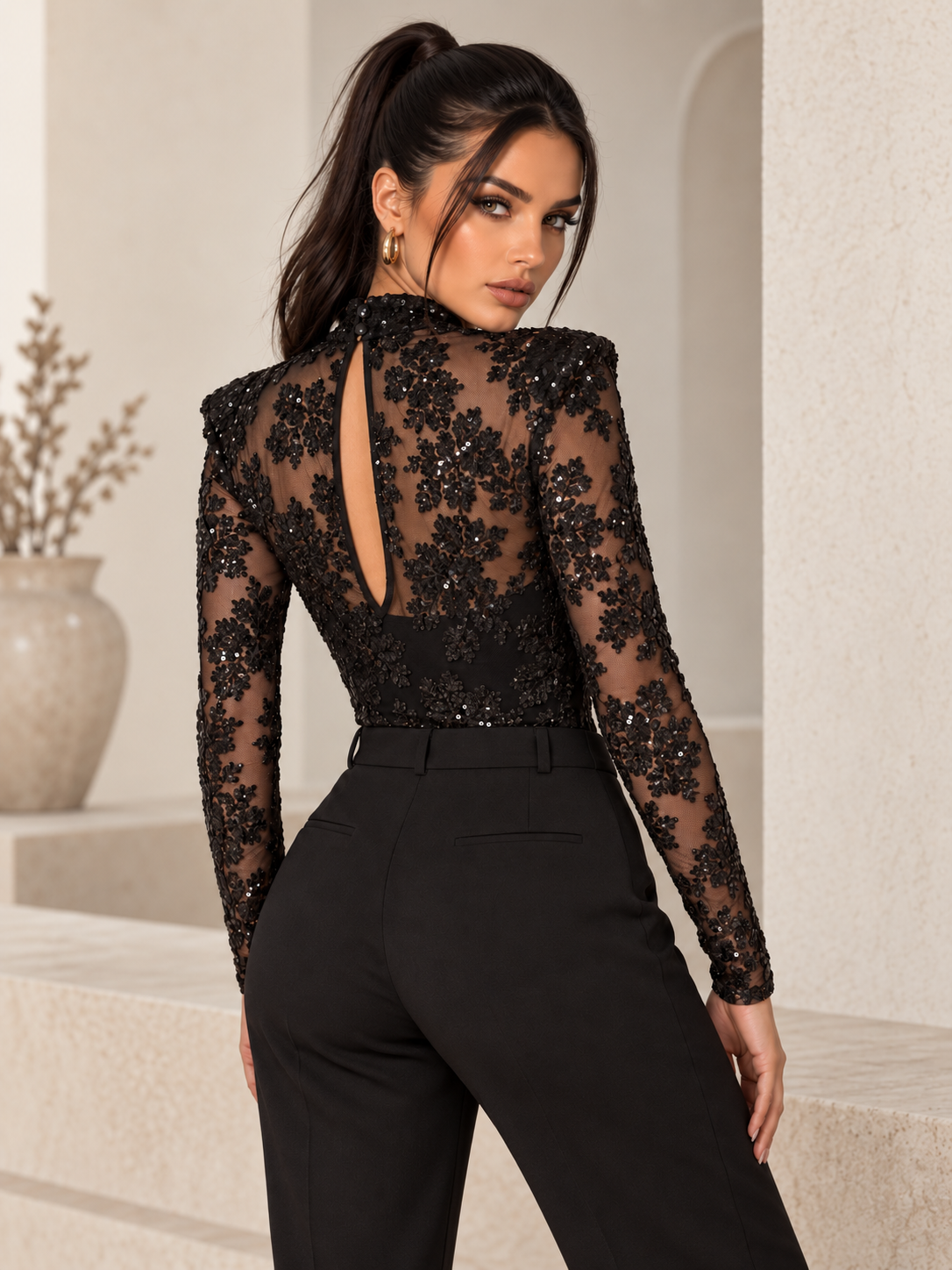 Body Odette Black in pizzo nero con dettagli luminosi, collo alto e maniche lunghe: vista posteriore con apertura a goccia su modella – DIVAMODA.
